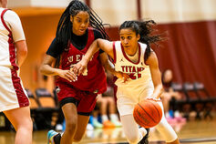 A women's basketball player dribbles around a defender.
